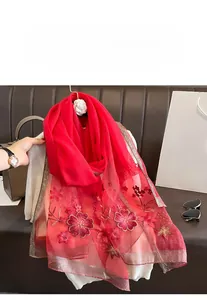 Close-up of red silk scarf featuring exquisite flower embroidery and metallic ribbon edging