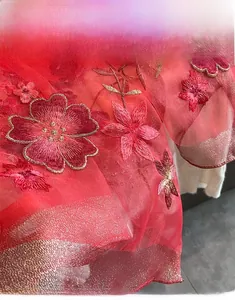 Detail of red silk wool scarf featuring pink floral embroidery and gold machine edging