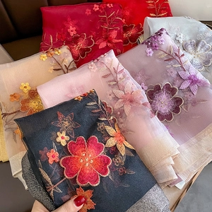 Detailed close-up of intricate floral embroidery on lightweight faux silk scarves