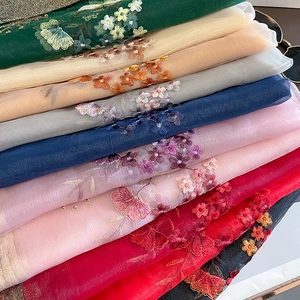 Detail showing various colors of lightweight embroidered tulle fabric with floral patterns