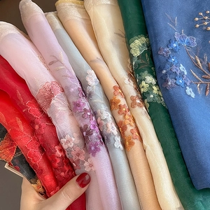 Detailed view of lightweight embroidered floral silk wool shawls in various vibrant colors