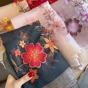 Close-up of floral embroidery on lightweight silk wool scarf with silver metallic edges
