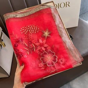 Detailed view of red silk scarf with pink floral embroidery and gold glitter trim