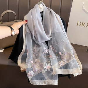Detail of floral embroidery on smoky gray silk wool scarf with metallic gold borders