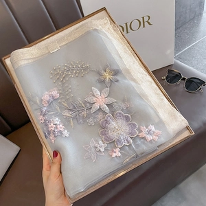 Detail of floral embroidery on light blue sheer silk wool scarf in a gift box