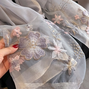 Close-up of premium grey silk wool shawl featuring detailed floral embroidery and sheer texture