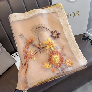 Detail of floral embroidery on sheer silk wool scarf with golden glitter edges
