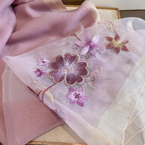 Close-up of pink silk wool scarf with intricate purple floral embroidery and gold stitching