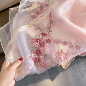 Close-up of pink silk-wool scarf with delicate floral embroidery and metallic edges