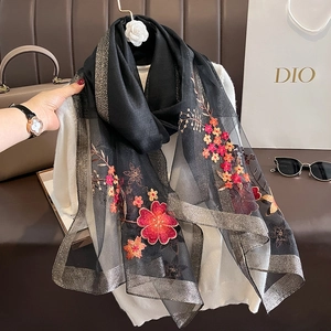 Detail of floral embroidery on black silk wool scarf with golden glitter edges