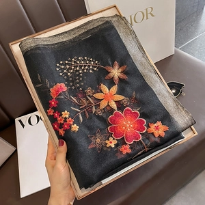 Detail of silk wool scarf with intricate floral embroidery and gold metallic edges