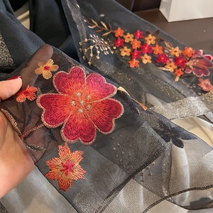 Macro detail of silk wool scarf showing floral embroidery with gold metallic thread
