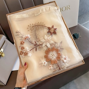 Detail of elegant silk wool scarf featuring intricate floral embroidery and sheer fabric