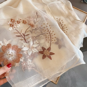 Detailed embroidery on translucent beige silk wool shawl with golden floral patterns