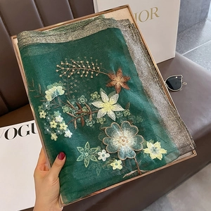 Detailed close-up of dark green silk wool scarf with intricate floral embroidery