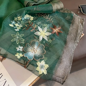 Close-up of floral embroidery on dark green semi-transparent silk-wool blend shawl