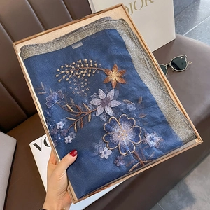 Close-up of floral embroidery on navy blue wool silk scarf with silver silk edges
