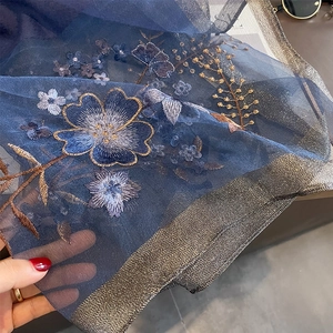 Detail of floral embroidery on navy mesh fabric with metallic silk edge for shawls