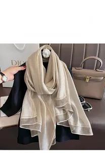 Detail of silk-like scarf featuring fine vertical texture and metallic trim accents