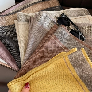 Detailed view of striped silk scarf texture with shimmering metallic gold thread accents