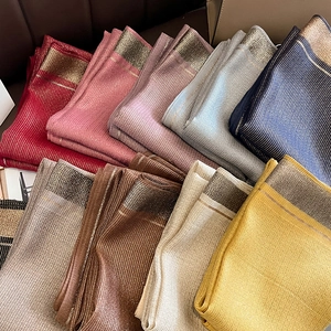 Detail of multi-color silk scarves featuring metallic thread stripes and elegant wide borders