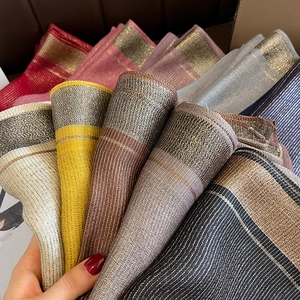 Close-up of striped silk scarf texture with shimmering metallic threads and multi-color fringe