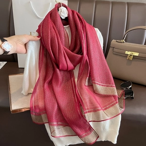 Detail of red silk scarf with gold metallic stripes draped over a white turtleneck