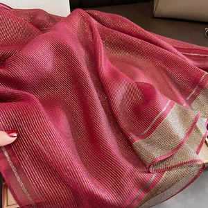 Close-up of elegant red silk shawl with gold metallic silk stripes and shimmering texture