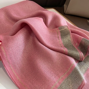 Detailed texture of pink silk scarf with gold lurex shimmer and metallic stripes