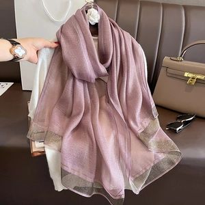 Detailed texture of lavender silk scarf with gold stripes draped on white clothing
