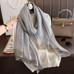 Detail of grey silk-like scarf featuring metallic silver lurex edges on a soft texture