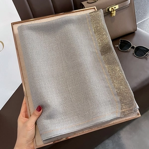 Detail of grey silk scarf with elegant gold metallic stripes in a gift box