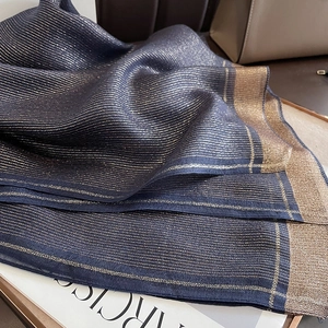 Macro detail of navy silk scarf featuring fine gold lurex stripes and elegant woven edges