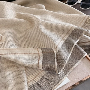 Detailed close-up of champagne silk scarf with metallic texture and striped borders