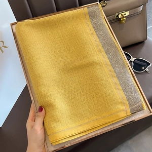 Detail of yellow silk-like scarf with gold glitter edges in luxury gift box packaging
