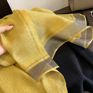 Detail of yellow silk-like scarf with shimmering metallic gold threads and sheer texture
