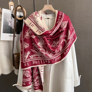 Detailed shot of burgundy floral scarf with fringe on coat and leather bag