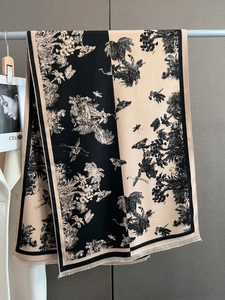 Détail de l'imprimé fleurs et papillons sur une écharpe beige et noire à franges