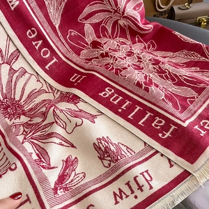 Close-up of thick floral scarf with fringe detail and Falling in love typography