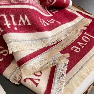 Detail of red and cream winter shawl with love lettering and fringe tassels