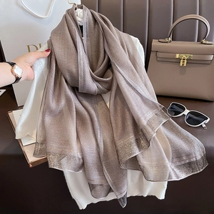 Detail of taupe silk scarf with metallic vertical stripes styled with fashion accessories