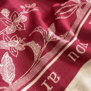Detail of red winter scarf featuring delicate white floral prints and soft textile texture
