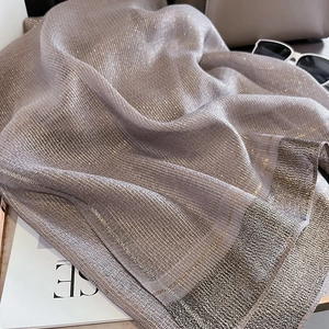 Detail view of champagne silk scarf with subtle shimmer finish and grey contrast border
