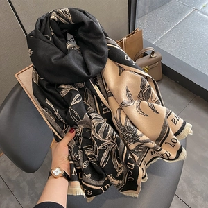 Detail of floral and letter print scarf with fringe edges in black and beige tones