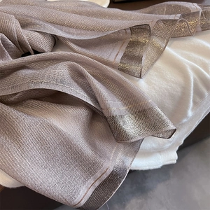 Detail of elegant champagne silk scarf featuring shimmering metallic threads and wide hem