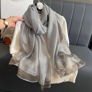 Detail shot of shimmering silver silk scarf featuring metallic gold and coffee striped edges