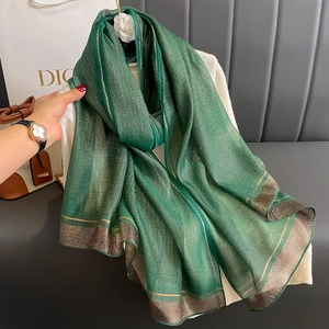 Detail of green silk scarf with metallic gold stripes and wide gold border edges