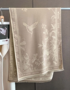 Detail view of khaki scarf with floral hummingbird pattern and elegant short fringe finish