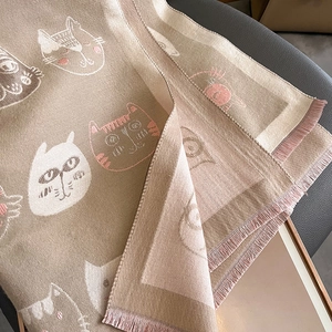 Détail d'une écharpe en cachemire avoine avec motifs chats et bords à franges