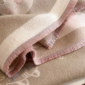 Gros plan d'une écharpe en cachemire beige avec franges roses et motifs de chat tricotés